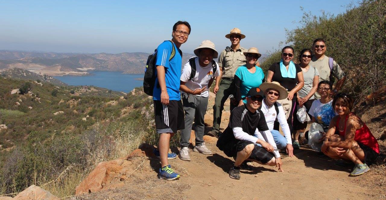 Group of hikers smiling at the top of the trail at Oakasis with a vista view