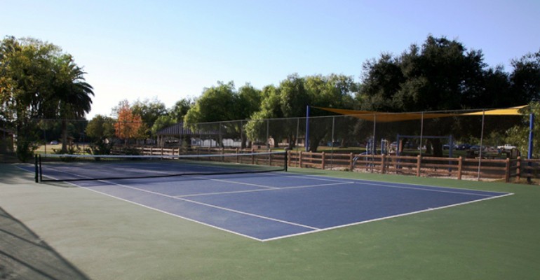 Tennis and picleball court with playground in the background.