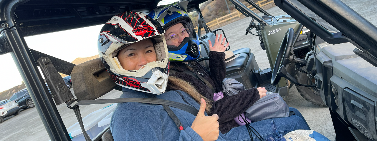 Voluntters in a polaris with safety equipment on giving a thumbs up